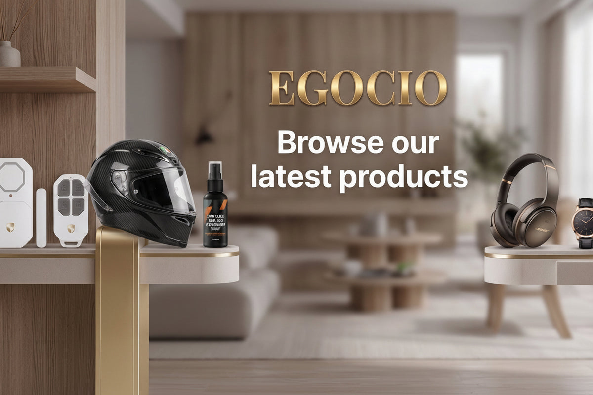 Promotional banner for EGOCIO showing a black motorcycle helmet, a small bottle, white electronic devices, over-ear headphones, a smartwatch, and a keyboard arranged on floating shelves in a modern interior. Large text reads 'EGOCIO Browse our latest products' with a 'Shop all' button.